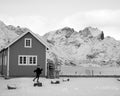 Person walking in front of a snowy cabin with mountains in the background